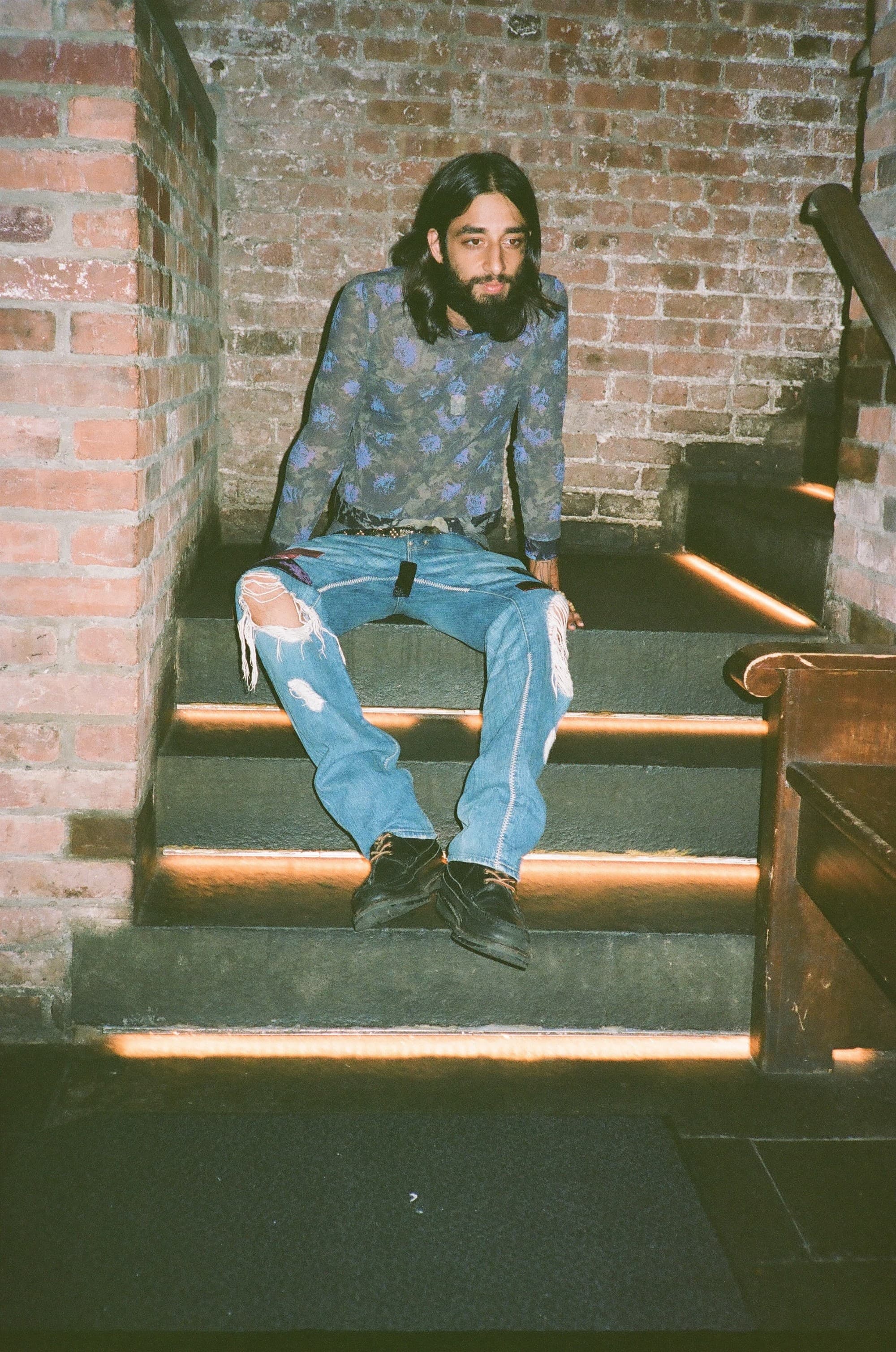 A model in an Issey Miyake flower mesh top seated on a staircase